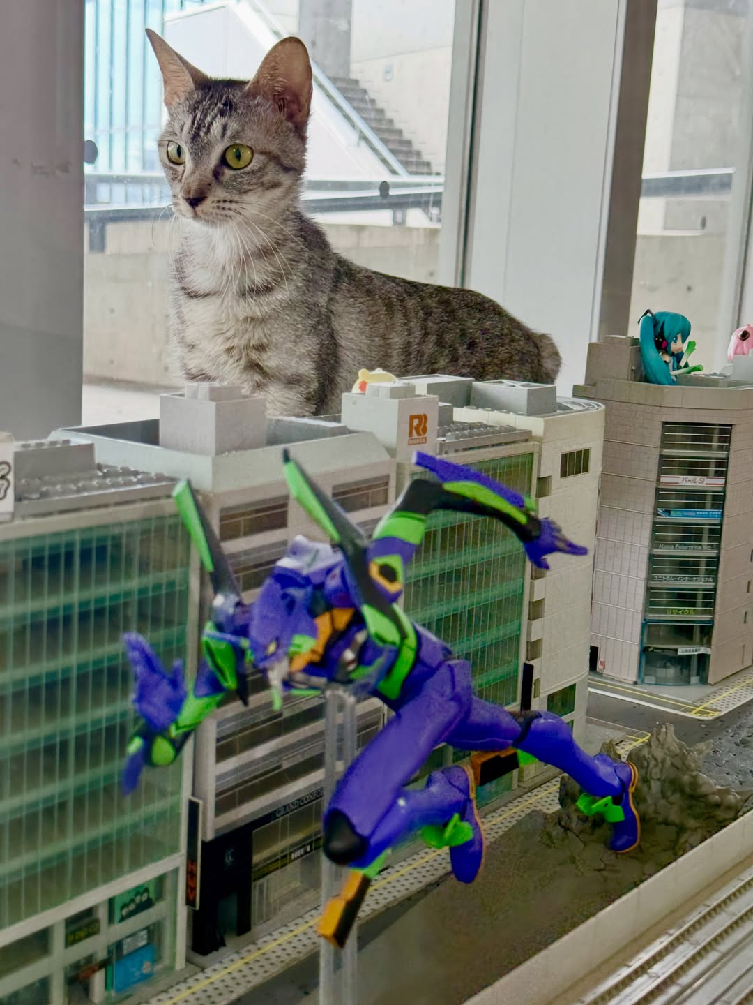 ジオラマのフィギュアのそばでこちらを見る猫